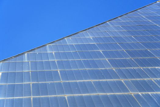 Detail of pyramid shaped glass building and blue sky