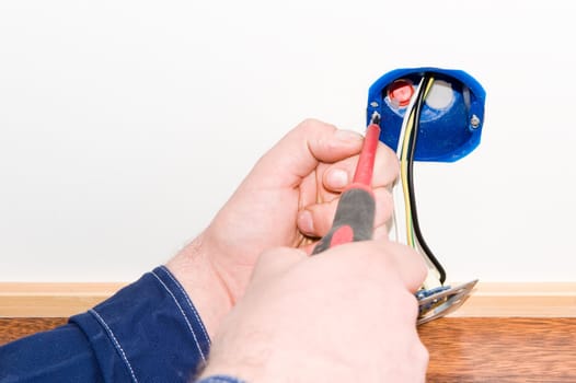 Electrician mounting a power outlet in wall.