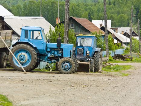 The image of two tractors costing in rural street.