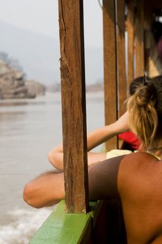 Passengers on a boat down the Mekong river in Laos. Brings a good holiday feeling of relaxation and all the time in the world. 