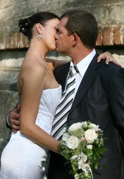 The groom and the bride kiss in park