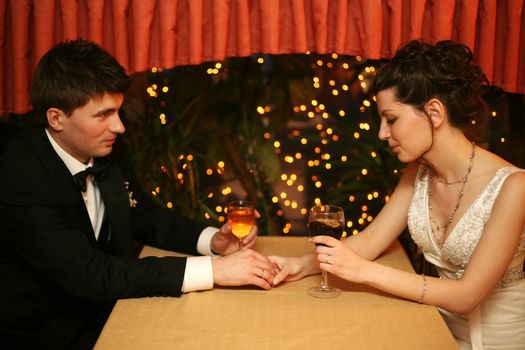 Newly-married couple sharing a glass of wine in restaurant, celebrating or on romantic date
