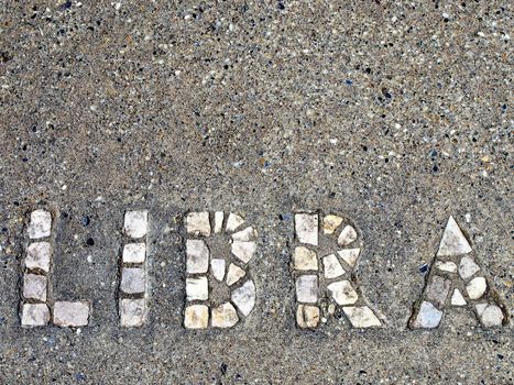 The astrological sign Libra spelled out in tile embeded in cement.
