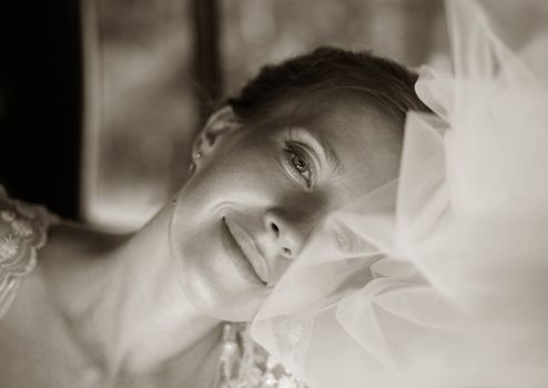 The beautiful bride in a veil gently smiles