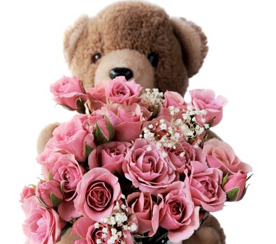 a teddy bear holds a bouquet of pink roses with baby's breath