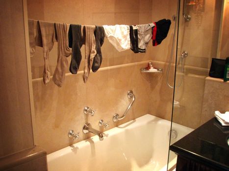 Image of socks and underwear hanging on a string drying over the bathtub.