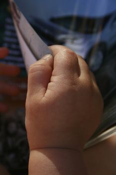 toddler turning the page of a magazine. Picture of a car in the background.