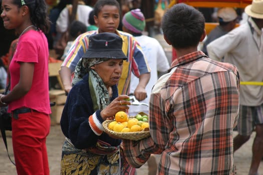 Elderly lady in Madagascar picking out the freshest lemons from a vendor