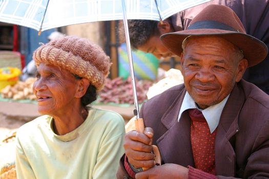 Elderly couple very sensibly hiding under an umbrella from the harsh middaysun in Madagascar