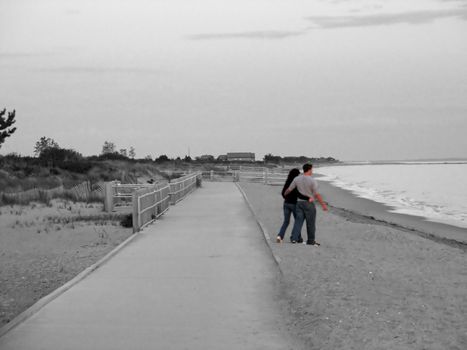 a young couple walking on the beach - isolated in color