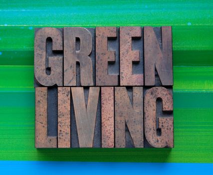 the words 'green living' in letterpress wood type on a green and blue background