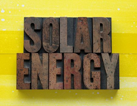 the words 'solar energy' in letterpress wood type on a yellow and white background