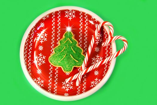 Green christmas tree cookie with candy canes on red plate