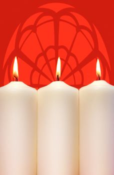 Three white holidays candles on a red background