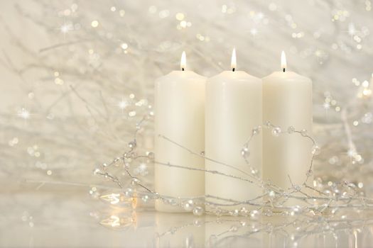 Three white candles with shimmering background for the holidays