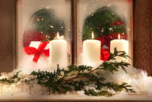 Three white candles in a frosted window