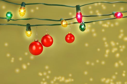 Three red christmas balls hanging on a set of colored tree lights