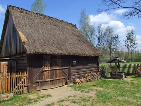 Old wooden hut in village, green grass around