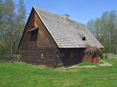 Old wooden hut in village, green grass around