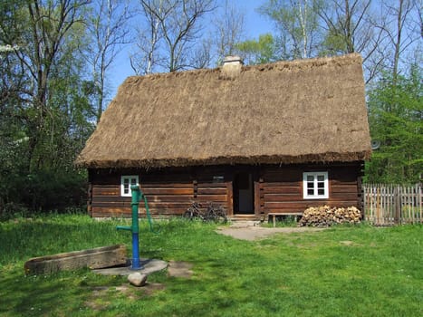 Old wooden hut in village, green grass around