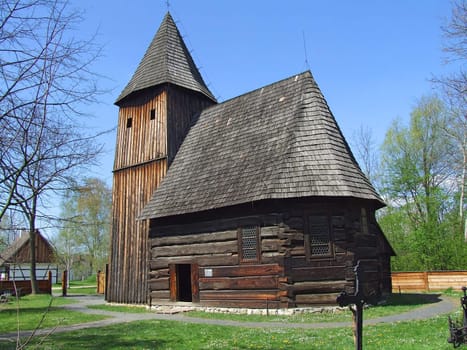 Old wooden church in village, green grass around