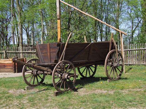 Old wooden wagon in village, green grass around