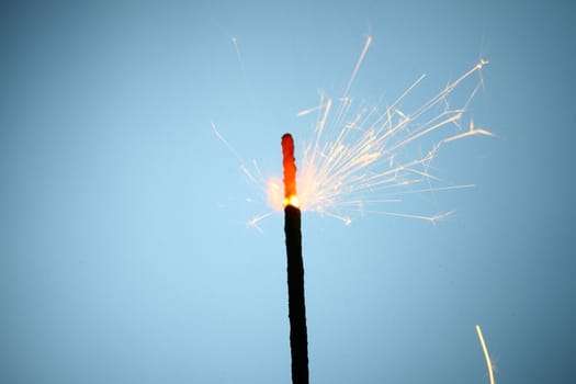 sparkler fire on blue macro background close up