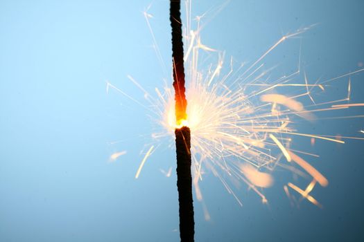 sparkler fire on blue macro background close up