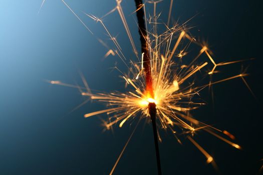 sparkler fire on blue macro background close up