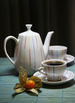 Two cups and a teapot on a green wooden napkin