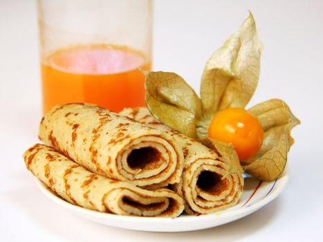 Pancakes on a plate and a glass with carrots juice
