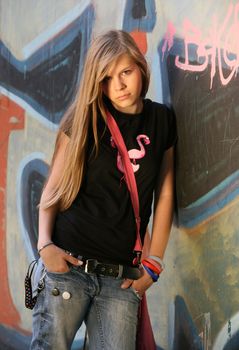 The young girl on a background of a wall with graffiti