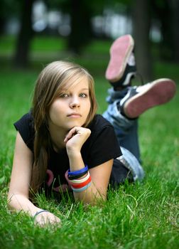 The girl - teenager lays in a grass.