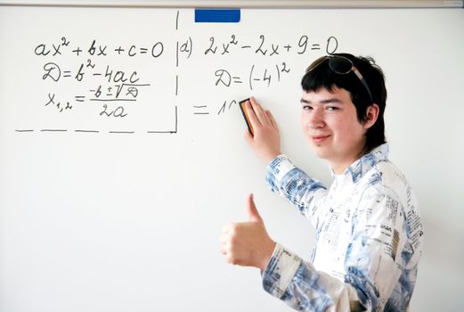 Young teacher teaching algerbra  and writes quadratic equation on a whiteboard