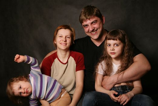 Family portrait on a dark background in studio