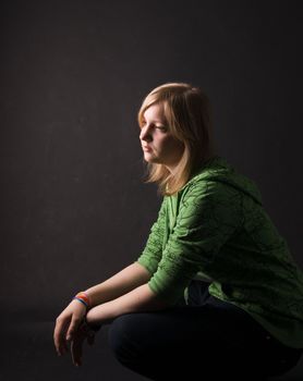 The young girl in green clothes on a black background.