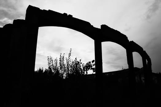 Silhouette of a rotting ruin of a curved industrial building. A fire once destroyed the whole area, these are the spooky remains.