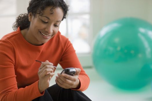 Young smiling African American woman text messaging on cell phone 