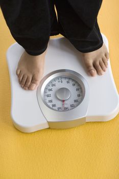 African American Woman weighing herself on a bathroom scale