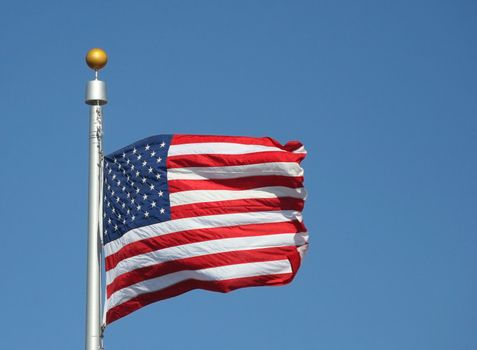 The flag of the United States of America waving in the wind against a bright blue Colorado sky
