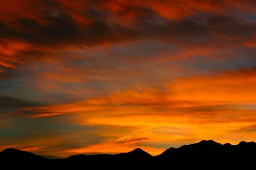 Brilliant, luminous shades of yellow, and orange streak the skies over the Rocky Mountains during an autumn sunrise.