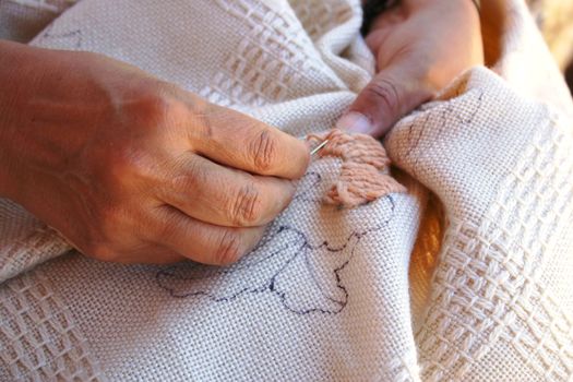 Woman using bright woolen yarn to embroider fabric