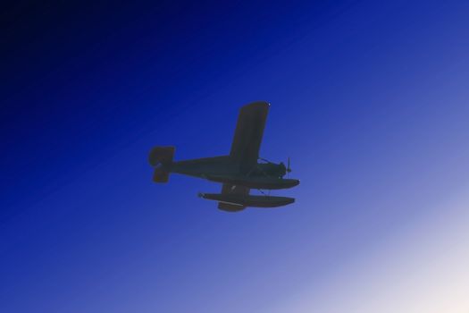 A small sea plane flies through the Alaskan skies