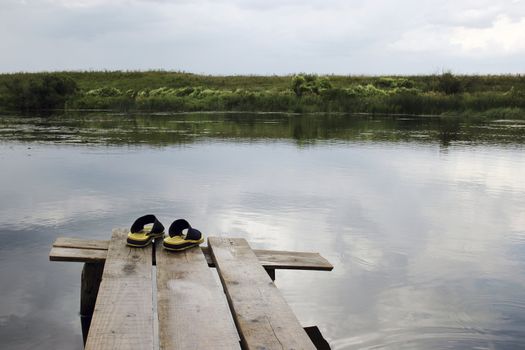 Yellow rubber slippers on wooden bridge