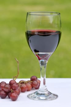 Close up of a glass of red wine on a white tablecloth in the garden
