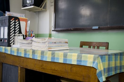 A teacher's desk and a chalkboard in an schoolroom 