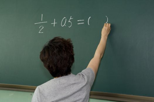 Female teacher writing on a blackboard 