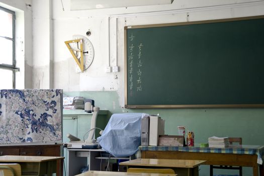 A teacher's desk and a chalkboard in an schoolroom 