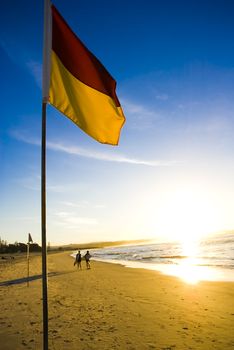 A surf life saving flag in Australia to mark the safe place to swim at the beach just before sunset