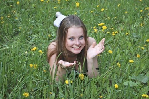 beautiful girl on summer lawn with dandelions